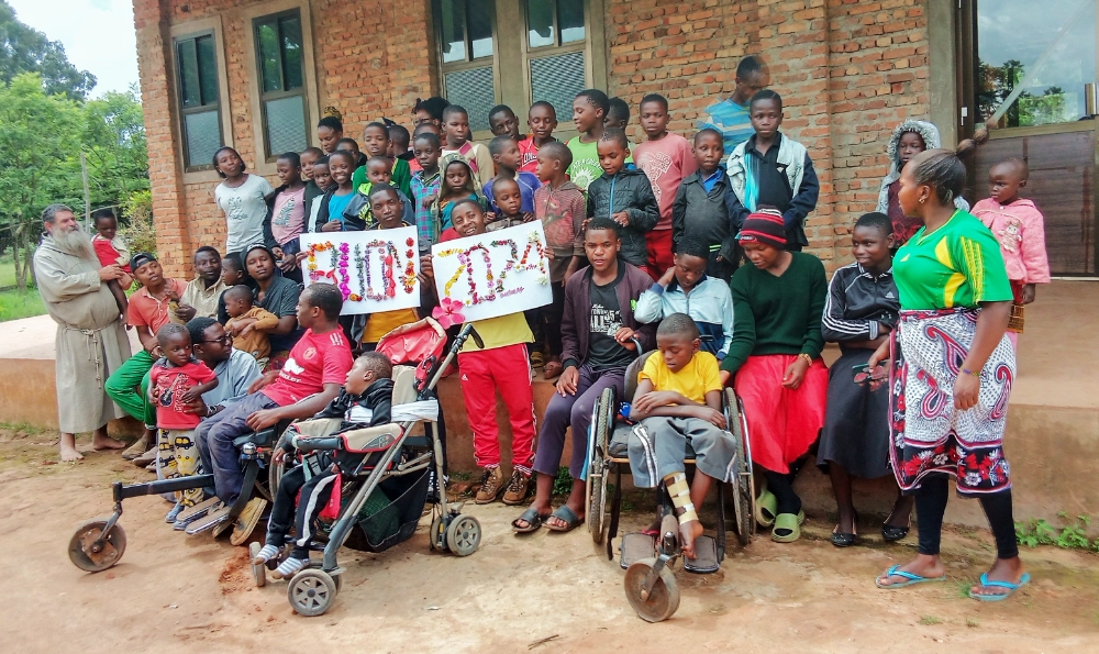 A diverse group of community members, including children and individuals with special needs, gathered together happily, representing the inclusive mission of our Community Development NGO in Kilolo.