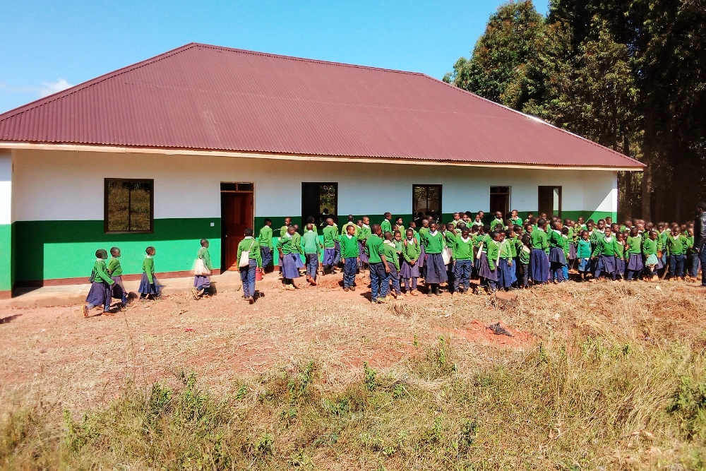 Students in green and blue uniforms gather outside a newly constructed school building, representing the education infrastructure projects supported by our Community Development NGO in Kilolo, Iringa.